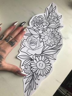 a woman's hand holding up a sticker with flowers and leaves on it