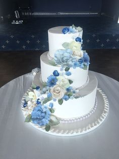 a three tiered cake with blue and white flowers