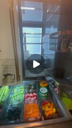 a person standing in front of a refrigerator filled with lots of different types of vegetables