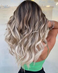 the back of a woman's head with long, wavy hair in front of a store window