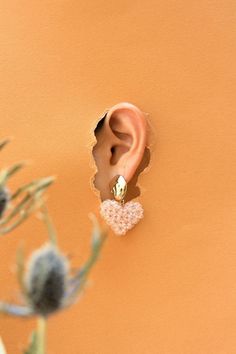 an ear is seen through a hole in the wall next to a plant with flowers