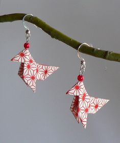 two red and white origami stars hanging from a tree branch with silver earwires