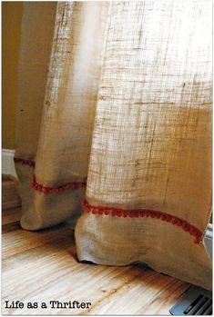 a curtain with red trim on it sitting next to a window