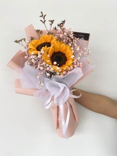 a bouquet of sunflowers and baby's breath tied to a pink ribbon