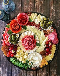 a platter filled with different types of cheeses and vegetables on top of a wooden table