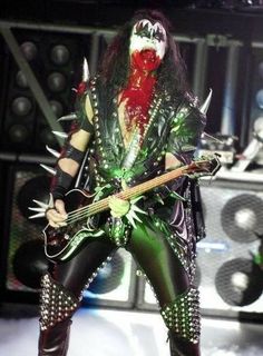 an image of a man that is on stage with a guitar and some lights in the background