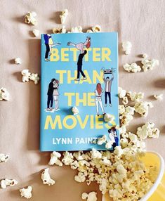 a book sitting on top of a table next to a bowl of popcorn