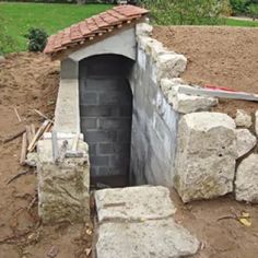 an outdoor oven built into the side of a hill with rocks and bricks around it