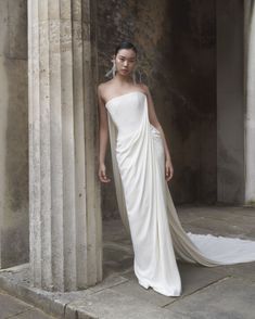 a woman in a white dress standing next to columns