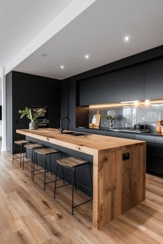 a large kitchen with wooden floors and black cabinets, along with an island countertop