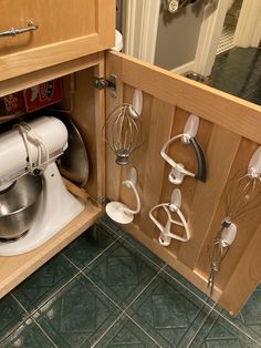 a kitchen cabinet with many attachments and mixers on the door handle in it