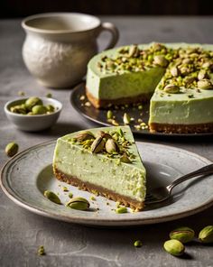 there is a piece of green cake on the plate and another slice has pistachios