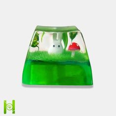 a green vase with two white rabbits in the grass and one red mushroom behind it