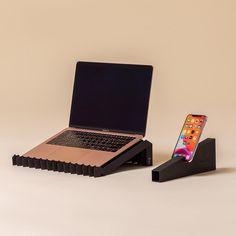 an open laptop computer sitting on top of a wooden stand next to a cell phone