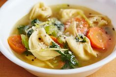 a white bowl filled with pasta and veggies in broth, cheese and parmesan