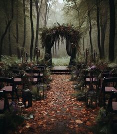 an outdoor ceremony set up in the middle of a forest with lots of leaves on the ground