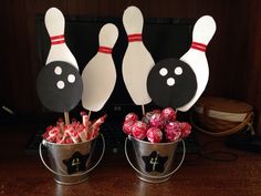 two buckets filled with candy and bowling pins sitting on top of a wooden table