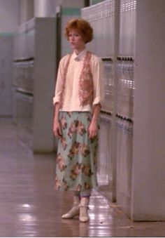 a woman standing next to lockers in a hallway with her hands on her hips