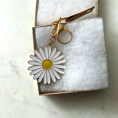 a white and yellow flower keychain in a box