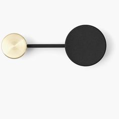 a black and gold wall mounted hook on a white wall with a round knob in the middle