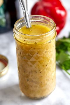 a jar filled with yellow liquid sitting on top of a table next to some vegetables