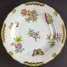 an old china plate with flowers and birds on it's rim is sitting on a black surface