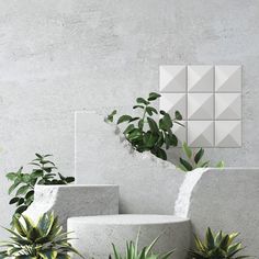 three cement planters sitting next to each other in front of a wall with plants on it