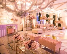 a room filled with lots of furniture and flowers on top of tables in front of a chandelier