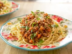 spaghetti with meat sauce and parmesan cheese on a floral plate, ready to be eaten