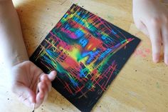 someone is drawing on a piece of paper with colored crayons