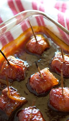 meatballs with toothpicks in a glass dish on a tableclothed towel