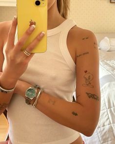 a woman taking a selfie with her cell phone in front of her face and tattoos on her arm