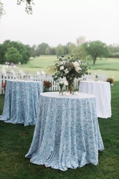 the table is set with white linens and flowers in vases on each side