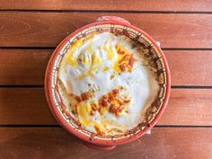 a red bowl filled with food on top of a wooden table