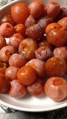 a white bowl filled with red fruit on top of a table