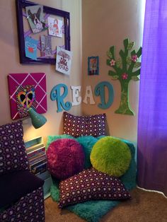 a bedroom with purple and green pillows on the floor next to a bed covered in books