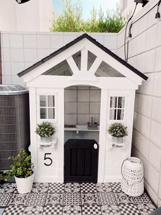 a small white doll house sitting on top of a black and white checkered floor