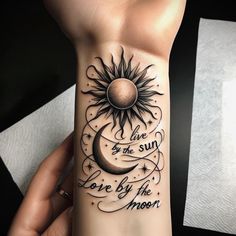 a woman's arm with a sun and moon tattoo on the wrist that says live by the sun, love by the moon