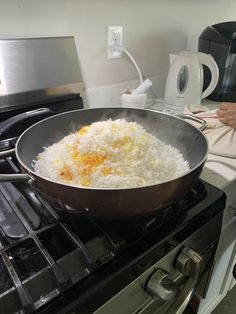 a pan filled with rice sitting on top of an oven next to a stove burner