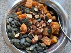 a metal bowl filled with nuts and pumpkins