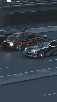 two cars driving on a race track next to each other with flames painted on them