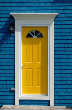 a yellow door on a blue brick building