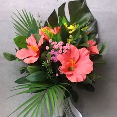 a vase filled with pink flowers and greenery on top of a table next to a wall