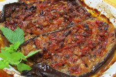 an eggplant dish on a plate with a sprig of mint