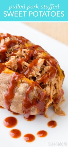 pulled pork stuffed sweet potatoes on a white plate with ketchup and barbecue sauce