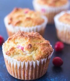 three cranberry muffins sitting on top of a table next to berries