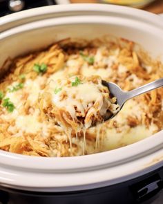 a close up of a spoon in a crock pot filled with lasagna casserole