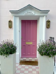 a pink door with two planters in front of it