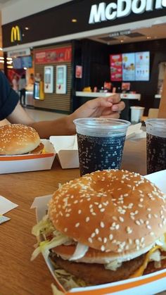 two large hamburgers sitting next to each other on top of a table in a fast food restaurant