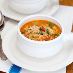 a white bowl filled with soup sitting on top of a plate next to silverware